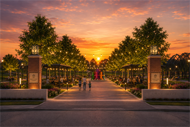 Photorealistic digital rendering of the Harvest Square park entrance at sunset. Brick gateway pillars lead to a pedestrian wide path lined with string lights, trees, shade structures, and a vibrant, multi-colored abstract sculpture at the center.