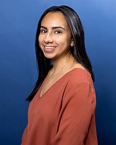 Photo of a girl in red shirt in front of a blue background.