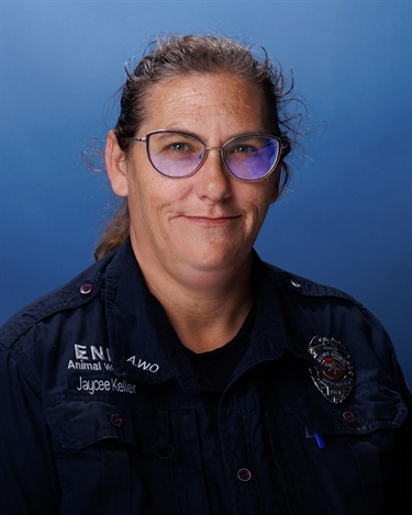 Photo of woman in animal welfare uniform and glasses in front of blue background